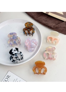 Detail shot of assorted tortoiseshell acetate hair claws on a ceramic plate