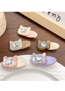Détail de pinces à cheveux chat en acétate avec strass incrustés sur une surface en bois