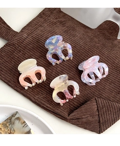 Close-up of four mini acetate hair claws with marble texture on brown corduroy background