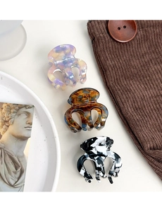 Detailed view of acetate hair claws in marble, amber, and ink patterns on vintage fabric