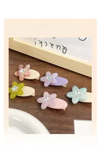 Set of five colorful floral hair clips with rhinestones on a rustic wooden background