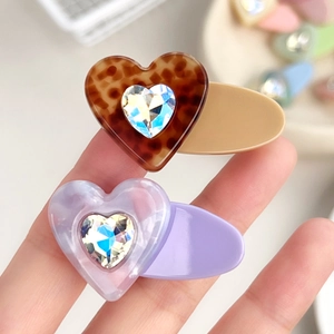 Set of two heart hair clips with leopard print and marble patterns held in hand