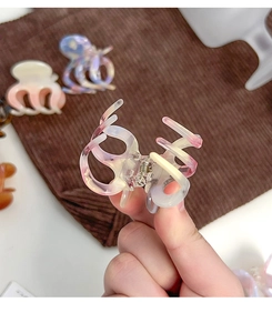 Detail view of a gradient floral acetate hair claw clip with cutout design and metal spring