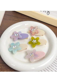 Set of five colorful star flower hair clips with rhinestones in a white ceramic dish