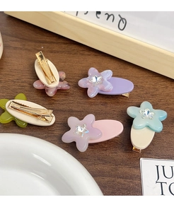 Detail of star-studded floral acetate hair clips in pastel colors on wooden surface