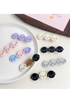 Detail of cute cartoon dog hair clips in pastel colors on a white ceramic plate