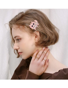 Detail of model wearing a pink cat-shaped hair clip with crystals and gold rings