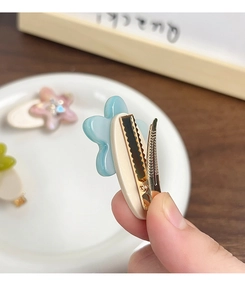 Detailed view of blue flower hair clip with golden metal alligator clip mechanism