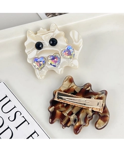 Detail of cat-shaped acetate hair clips with crystal heart and gold metal crocodile grip