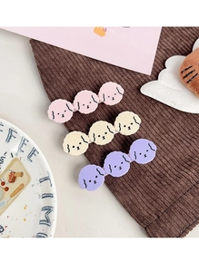 Three-piece cartoon puppy hair clips in pink, yellow, and purple on brown velvet