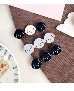 Detailed view of three cute cartoon puppy hair clips on brown corduroy fabric