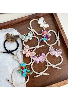 Détail d'élastiques à cheveux papillon en acétate coloré sur un plateau en bois