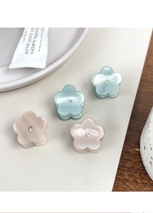 Détail de quatre mini pinces à cheveux fleur en acétate avec strass bleu et rose