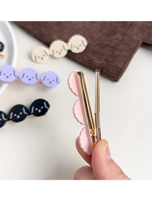 Detail showing the pink cartoon puppy hair clip with gold metal duckbill clip attachment