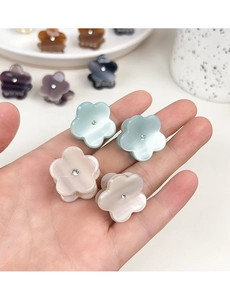 Détail d'une mini pince à cheveux fleur en acétate avec texture marbrée et strass
