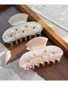 Détail de pinces à cheveux en acrylique pailleté avec des éléments décoratifs étoiles et lune