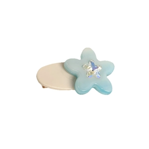 Cute light blue flower hair clip with a sparkling star accent on a cream base