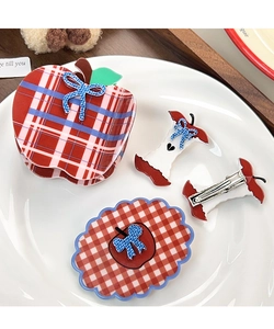 Detail of red plaid apple-shaped hair claw clip and hairpins with blue bow accents