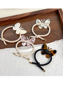 Détail de quatre élastiques papillon en acétate aux motifs crème, rose, bleu et écaille