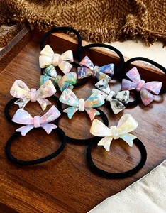 Detail of acetate bow hair ties with marble pattern displayed on a wooden tray