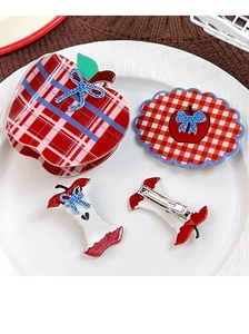 Red plaid apple hair claw and bow clip set displayed on a white ceramic plate