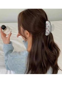 Détail d'une pince à cheveux argentée pailletée avec étoiles sur une coiffure