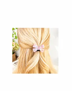 Pink marble acetate bow hair clip styled on light blonde hair for half-up hairstyle