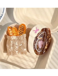 Detail of baking-themed acetate hair claws featuring baguette and croissant designs