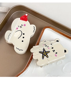 Detail of cream acetate hair claws featuring gingerbread man and teddy bear designs