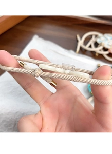Gros plan détaillé de l'élastique tissé beige avec fermoir doré et décor en acétate