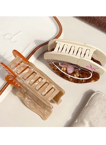 Detailed macro view of two minimalist acetate hair claws in beige and tortoiseshell patterns