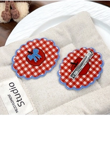 Detail view of red plaid apple hair clips showing both front design and metal duckbill clip