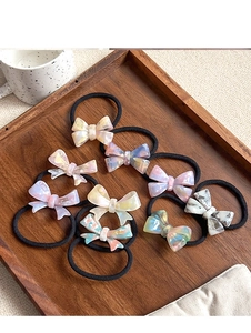 Detail of 8-piece acetate bow hair ties with marble texture on a wooden tray