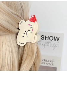 Detail of cute cream bear hair claw with red hat accent on blonde hair style