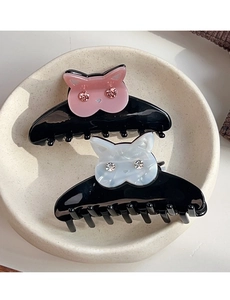 Gros plan sur des pinces à cheveux chat en acétate avec des yeux en strass rose et blanc
