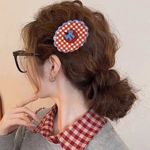 Retro red plaid flower hair claw with apple and blue bow detail on a female model