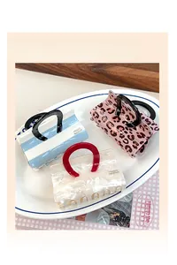 Detailed view of handmade acetate handbag shaped hair claw clips in striped and leopard patterns