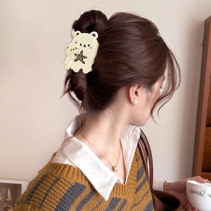 Cute cream bear hair claw clip for women's hairstyle shown on model in a cozy setting