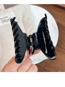Détail de la pince à cheveux papillon noir brillant avec ressort métallique pour coiffure