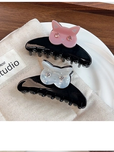 Vue détaillée de deux pinces à cheveux chat en acétate avec strass brillants sur tissu