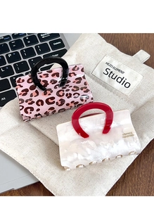 Detailed view of leopard and pearl white acetate hair claws on a canvas bag