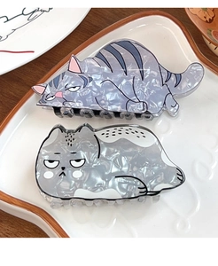 Detailed view of acetate cat-shaped hair claws on a ceramic tray with pearlescent finish