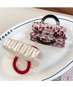 Close-up of leopard and pearl acetate hair claws in a ceramic tray for elegant styling