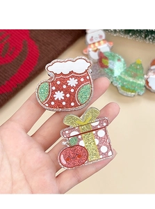 Detailansicht der glitzernden Acryl-Weihnachtssocken und Geschenkbox-Brosche in der Hand