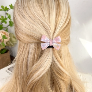Pink marble pattern acetate bow hair tie with elegant gold logo on blonde hair