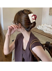 Detail of a large pearlescent hair claw clip with red rings on a brunette woman