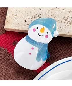 Detail der süßen Schneemann Haarklammer aus Acetat mit blauem Hut auf Winterstrickhintergrund