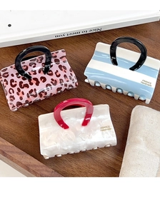 Three acetate handbag hair claws in pink leopard, blue stripes, and pearl white patterns