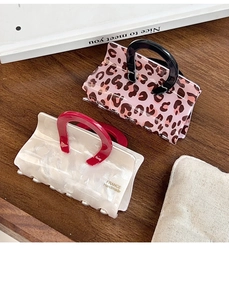 Detailed view of handmade acetate bag-shaped hair claws with leopard and pearl finishes