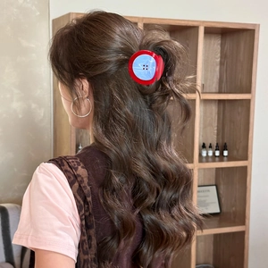 Pince à cheveux créative en forme de bouton rouge et bleu sur une coiffure